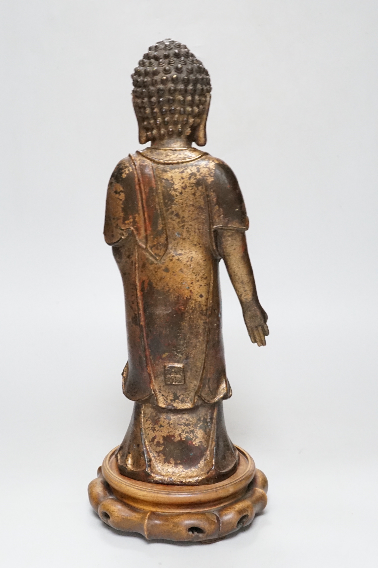 A Chinese gilt lacquered bronze standing figure of Buddha on stand, 31cm high not including stand